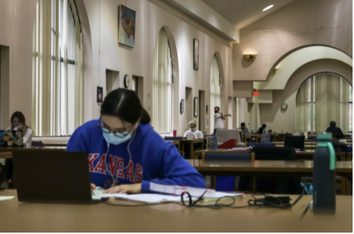 A woman studies in Anschutz Library while wearing a mask
