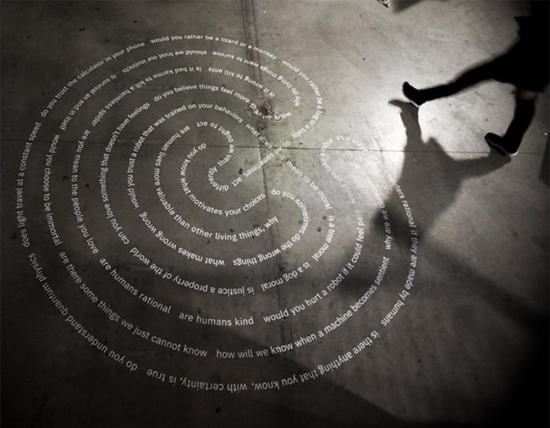 Projection of words in the shape of a fingerprint, titled Moral Labyrinth