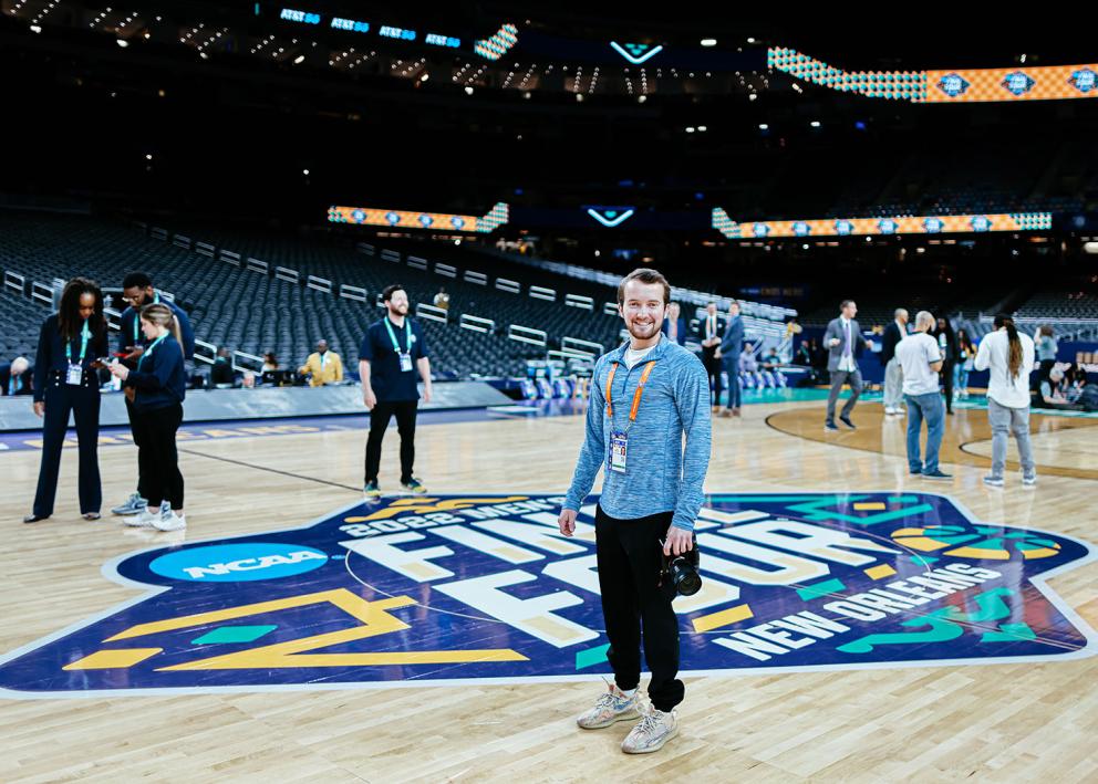 John Biehler standing in front of the Final Four logo at mid-court in the Superdome in April 2022.